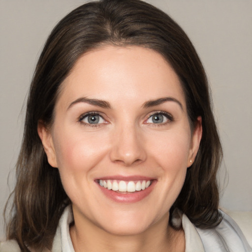 Joyful white young-adult female with medium  brown hair and grey eyes