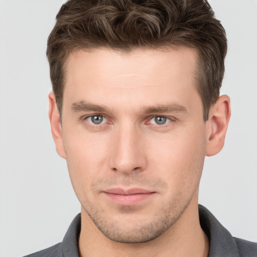 Joyful white young-adult male with short  brown hair and grey eyes