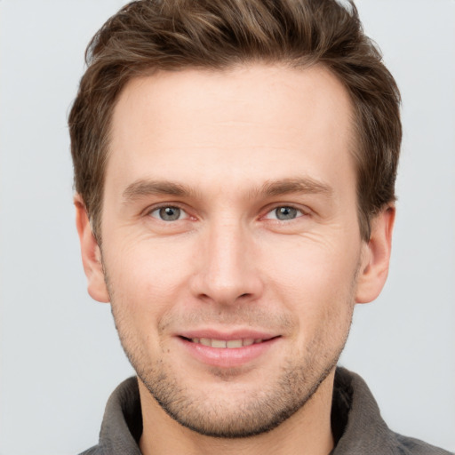 Joyful white young-adult male with short  brown hair and grey eyes