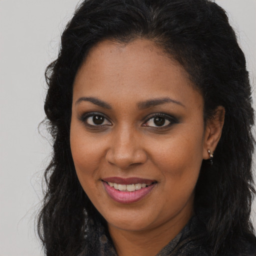 Joyful black young-adult female with long  brown hair and brown eyes