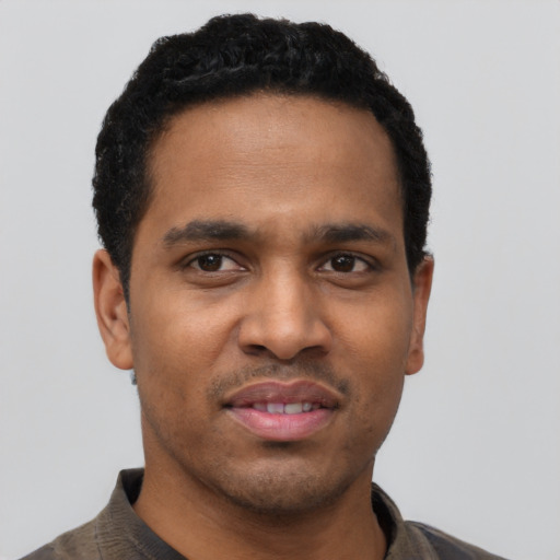 Joyful black young-adult male with short  black hair and brown eyes