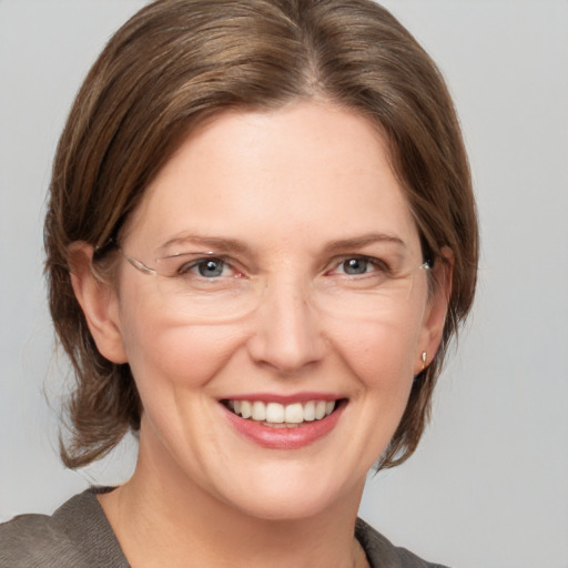 Joyful white adult female with medium  brown hair and grey eyes