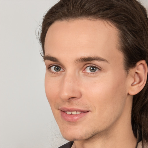 Joyful white young-adult male with long  brown hair and brown eyes