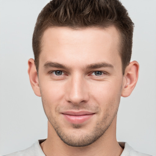 Joyful white young-adult male with short  brown hair and grey eyes