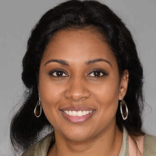 Joyful black young-adult female with long  brown hair and brown eyes