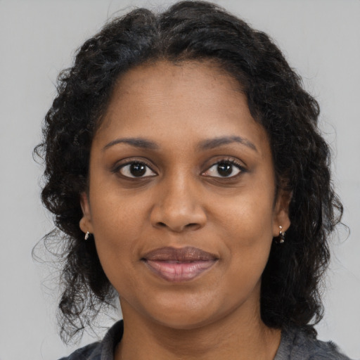 Joyful black adult female with long  brown hair and brown eyes