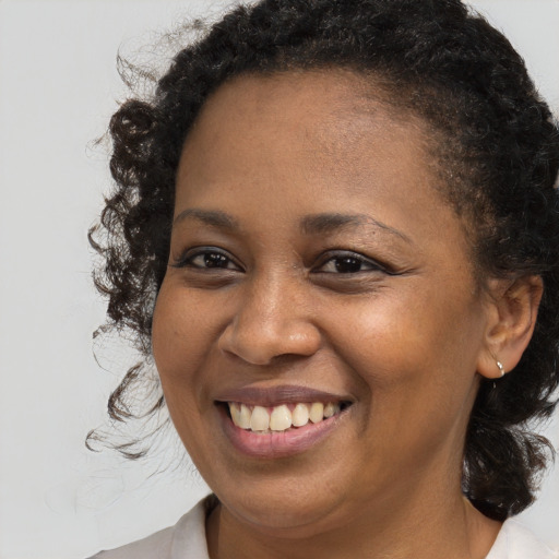Joyful black young-adult female with long  brown hair and brown eyes