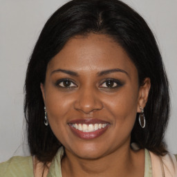 Joyful black young-adult female with long  brown hair and brown eyes