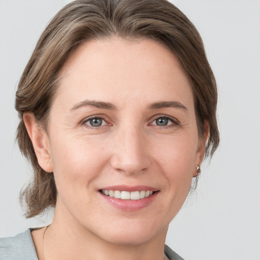 Joyful white young-adult female with medium  brown hair and grey eyes