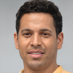 Joyful latino young-adult male with short  brown hair and brown eyes