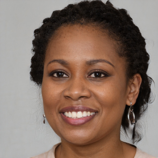 Joyful black young-adult female with long  brown hair and brown eyes