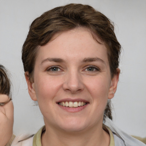 Joyful white young-adult female with medium  brown hair and grey eyes