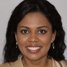 Joyful black young-adult female with long  brown hair and brown eyes