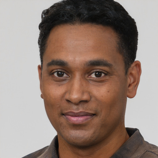 Joyful black young-adult male with short  black hair and brown eyes