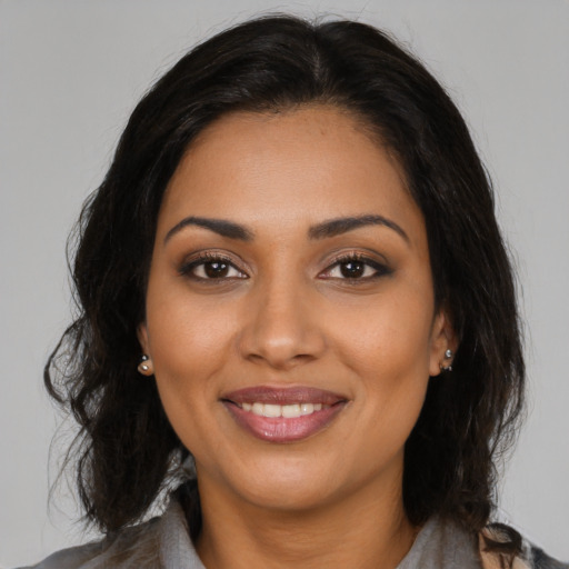 Joyful black young-adult female with long  brown hair and brown eyes
