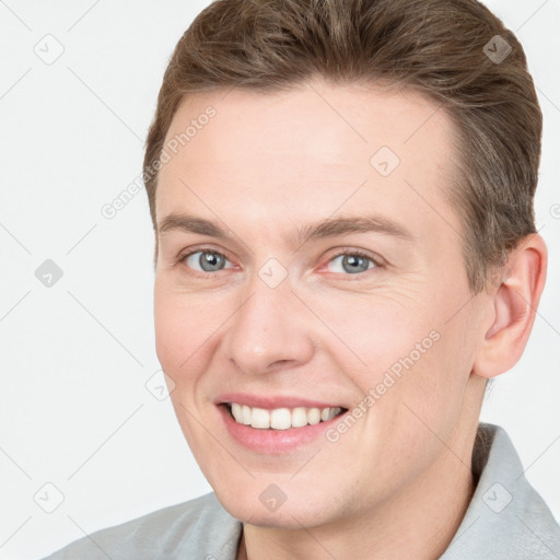 Joyful white young-adult male with short  brown hair and grey eyes