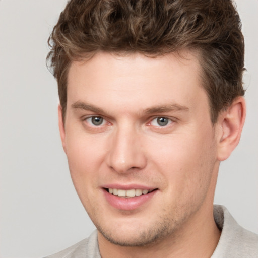 Joyful white young-adult male with short  brown hair and grey eyes