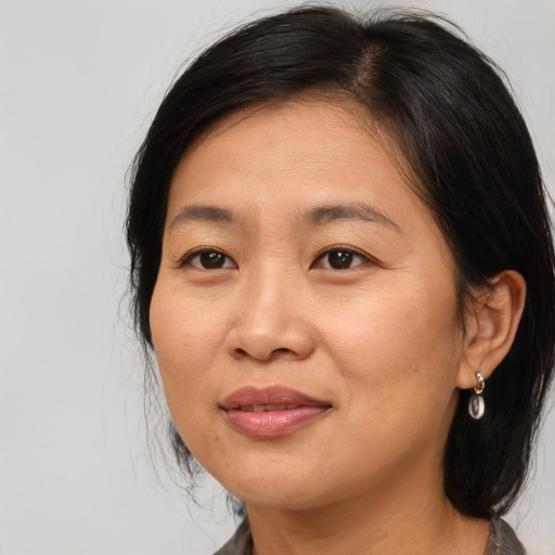 Joyful asian adult female with medium  brown hair and brown eyes