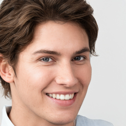 Joyful white young-adult male with medium  brown hair and grey eyes