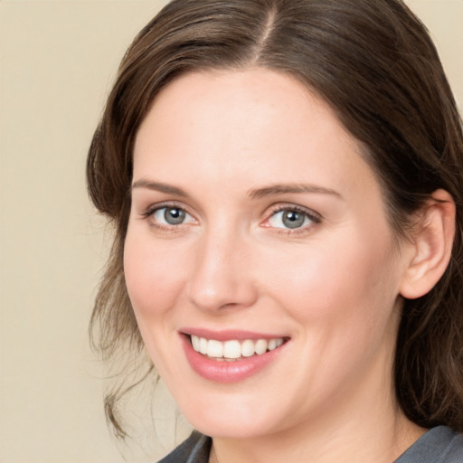 Joyful white young-adult female with medium  brown hair and grey eyes