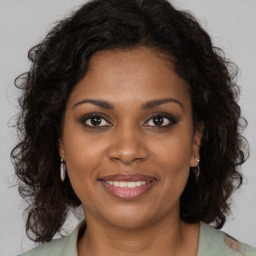 Joyful black young-adult female with long  brown hair and brown eyes