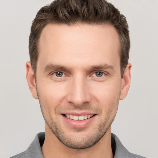 Joyful white young-adult male with short  brown hair and grey eyes