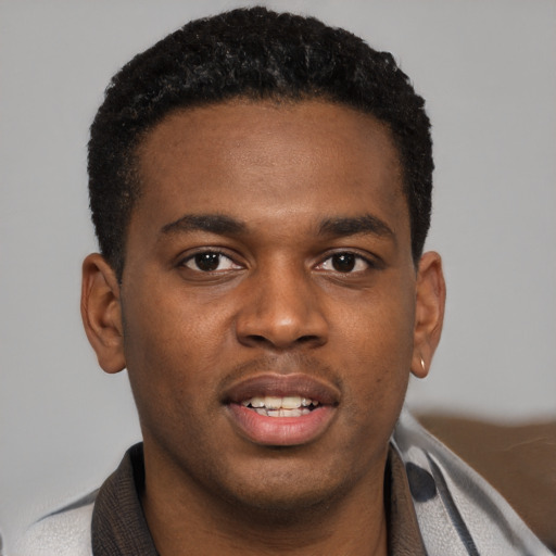 Joyful black young-adult male with short  black hair and brown eyes