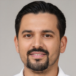 Joyful latino young-adult male with short  black hair and brown eyes