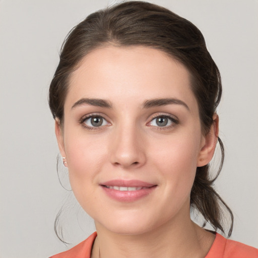 Joyful white young-adult female with medium  brown hair and grey eyes