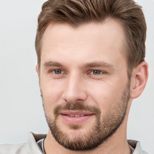 Joyful white young-adult male with short  brown hair and grey eyes