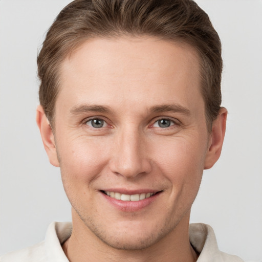 Joyful white young-adult male with short  brown hair and grey eyes