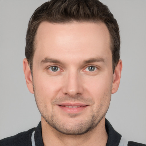 Joyful white young-adult male with short  brown hair and grey eyes