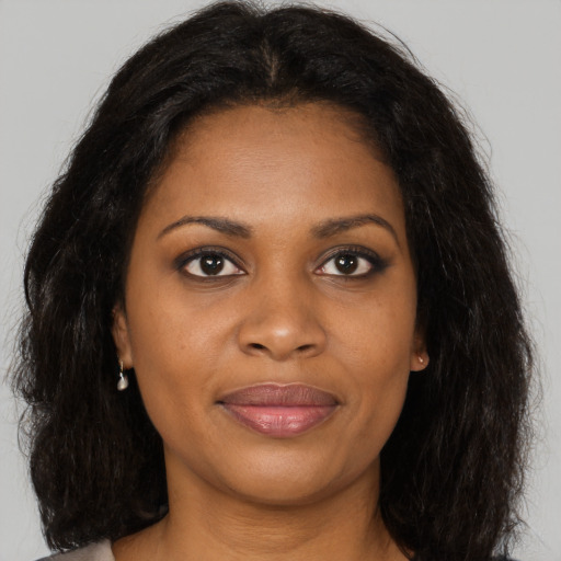 Joyful black young-adult female with long  brown hair and brown eyes
