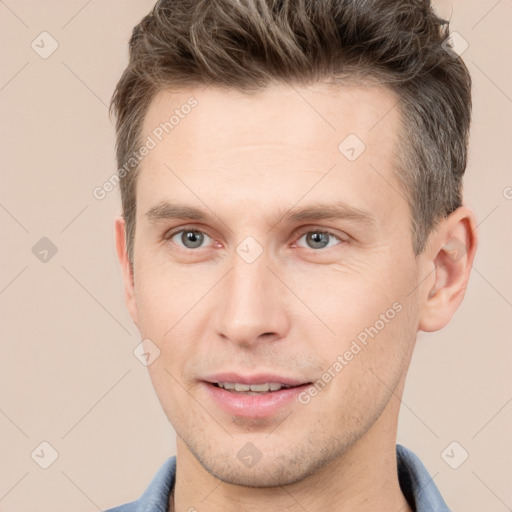 Joyful white young-adult male with short  brown hair and grey eyes