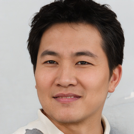 Joyful asian young-adult male with short  brown hair and brown eyes
