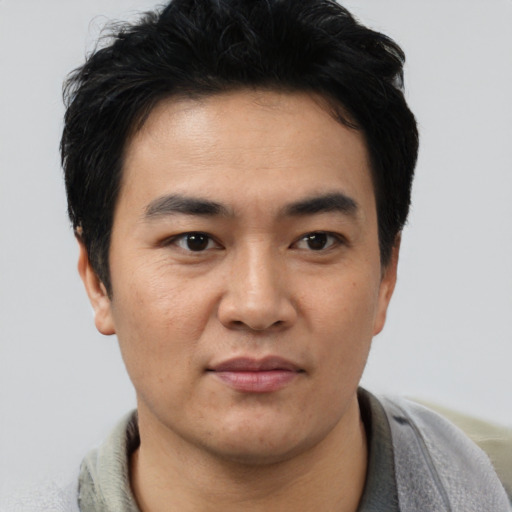 Joyful asian young-adult male with short  brown hair and brown eyes