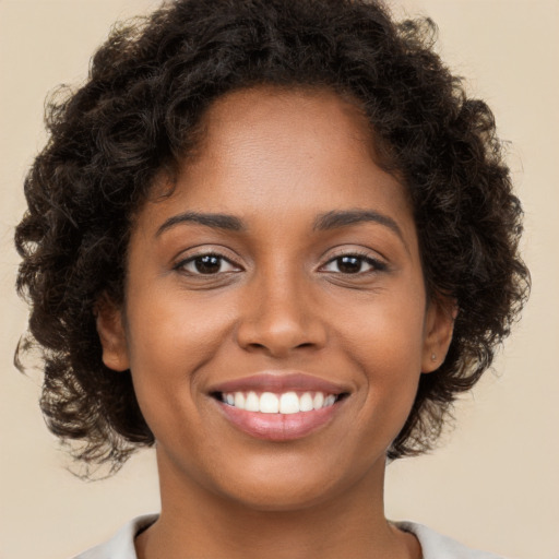 Joyful black young-adult female with long  brown hair and brown eyes