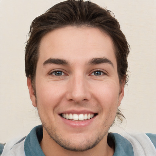 Joyful white young-adult male with short  brown hair and grey eyes