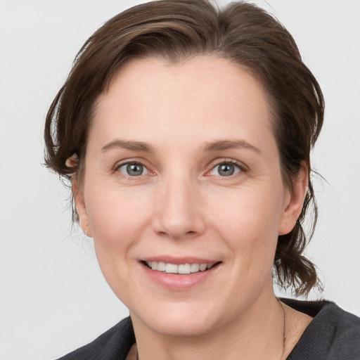 Joyful white young-adult female with medium  brown hair and grey eyes