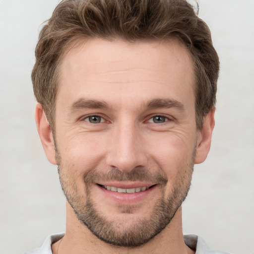 Joyful white young-adult male with short  brown hair and grey eyes