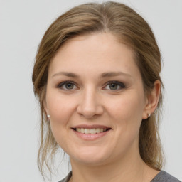 Joyful white young-adult female with medium  brown hair and grey eyes