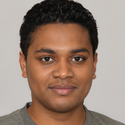 Joyful black young-adult male with short  black hair and brown eyes