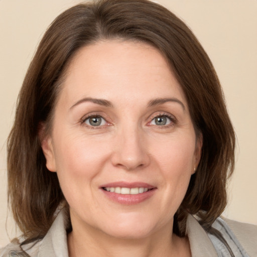 Joyful white adult female with medium  brown hair and grey eyes