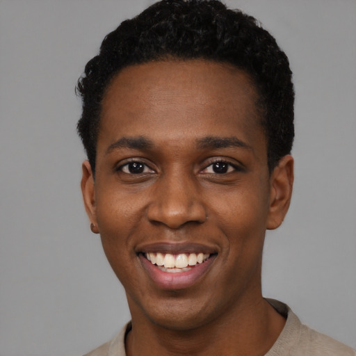 Joyful black young-adult male with short  black hair and brown eyes