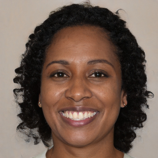 Joyful black adult female with medium  brown hair and brown eyes