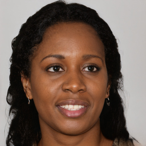 Joyful black young-adult female with long  black hair and brown eyes