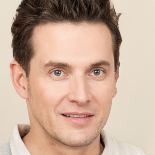 Joyful white young-adult male with short  brown hair and grey eyes