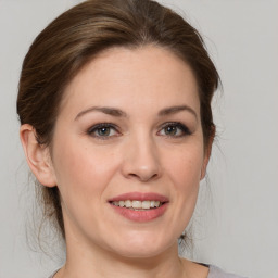 Joyful white young-adult female with medium  brown hair and grey eyes