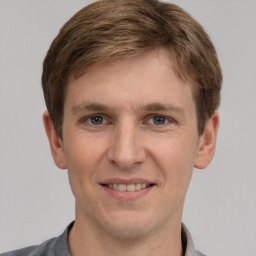 Joyful white young-adult male with short  brown hair and grey eyes