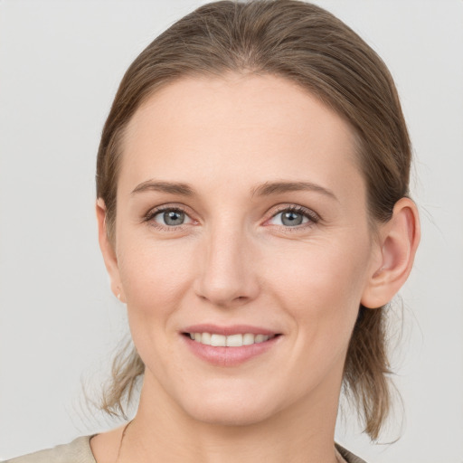 Joyful white young-adult female with medium  brown hair and grey eyes